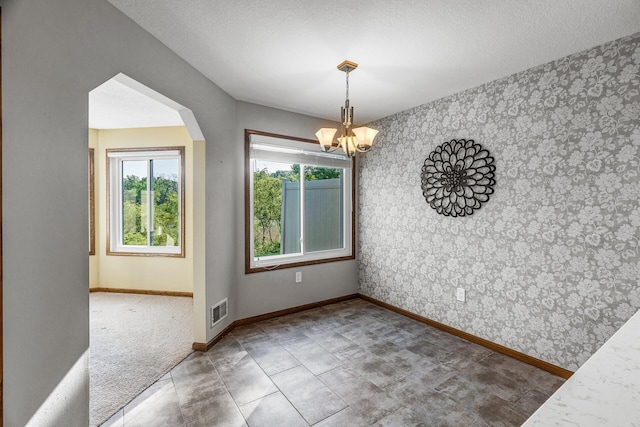 7582 Ojibway Park Bay, Woodbury, MN 55125 - unfurnished dining area featuring wallpapered walls, a chandelier, an accent wall, and arched walkways