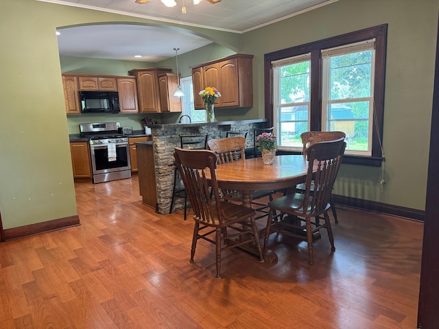 1315 Clark St W, Albert Lea, MN 56007 - dining space featuring ornamental molding, arched walkways, light wood-type flooring, and baseboards