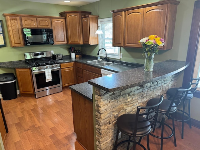 1315 Clark St W, Albert Lea, MN 56007 - kitchen with black microwave, stainless steel range with gas stovetop, a sink, a peninsula, and a breakfast bar