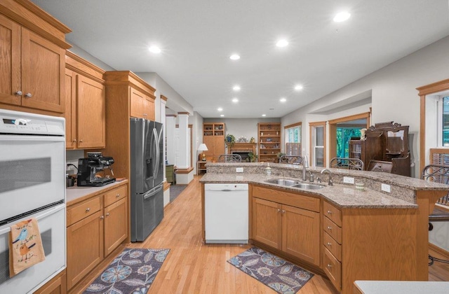 10426 Hidden Oaks Ln N, Champlin, MN 55316 - kitchen with white appliances, light wood-style flooring, recessed lighting, a kitchen breakfast bar, and a kitchen island with sink