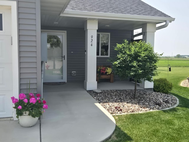 924 3rd Ave SE, Hayfield, MN 55940 - doorway to property featuring roof with shingles, covered porch, and a yard