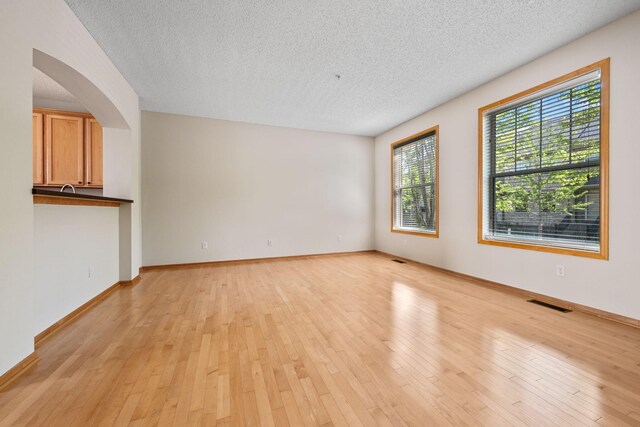 8280 Labont Way, Eden Prairie, MN 55344 - empty room with a textured ceiling, arched walkways, light wood-type flooring, and baseboards