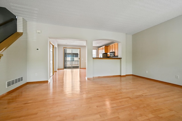 8280 Labont Way, Eden Prairie, MN 55344 - unfurnished living room featuring light wood finished floors, arched walkways, and baseboards