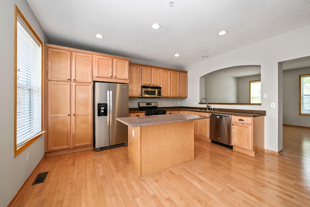 8280 Labont Way, Eden Prairie, MN 55344 - kitchen featuring appliances with stainless steel finishes, arched walkways, a kitchen island, light wood-style floors, and recessed lighting