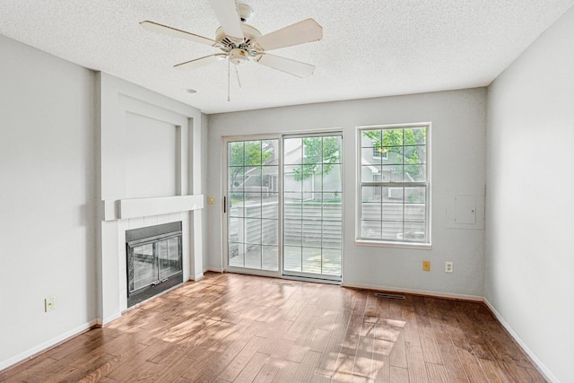 2040 Shenandoah Ct Unit B, Plymouth, MN 55447 - unfurnished living room with wood-type flooring, a tiled fireplace, ceiling fan, and a textured ceiling