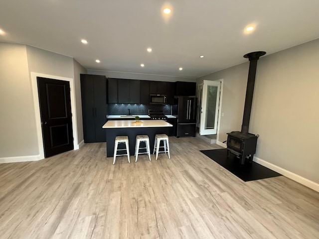 2120 Walden Blvd NW, Oak Grove, MN 55011 - kitchen with stainless steel microwave, freestanding refrigerator, dark cabinetry, a center island, and backsplash
