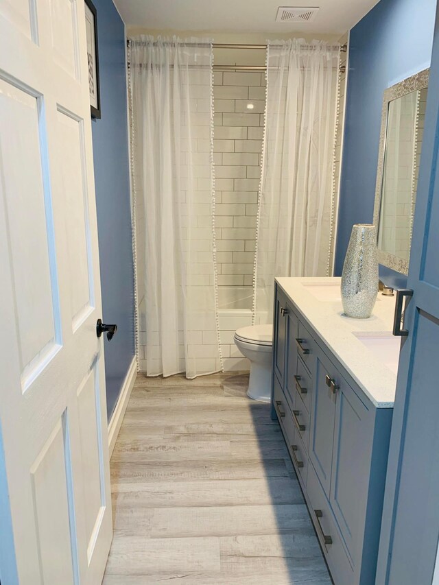 2120 Walden Blvd NW, Oak Grove, MN 55011 - bathroom featuring double vanity, shower / tub combo with curtain, and wood finished floors