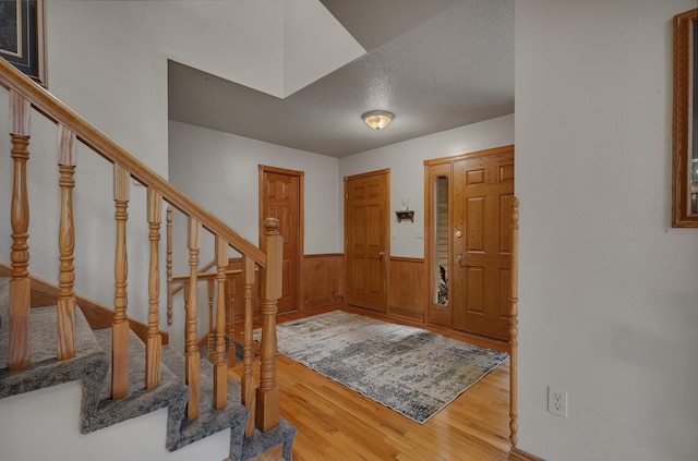 14789 Fireside Cir, Cold Spring, MN 56320 - entryway with a wainscoted wall, wood finished floors, stairs, wood walls, and a textured ceiling