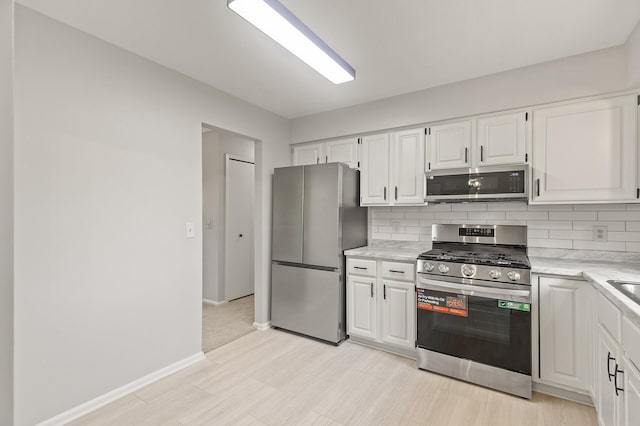 6716 83rd Ave N, Brooklyn Park, MN 55445 - kitchen with stainless steel appliances, decorative backsplash, white cabinetry, light wood-type flooring, and light stone counters