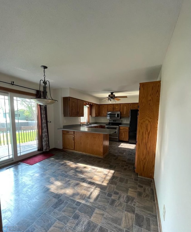 614 8th St E, West Fargo, ND 58078 - kitchen featuring appliances with stainless steel finishes, a peninsula, baseboards, brown cabinets, and a sink