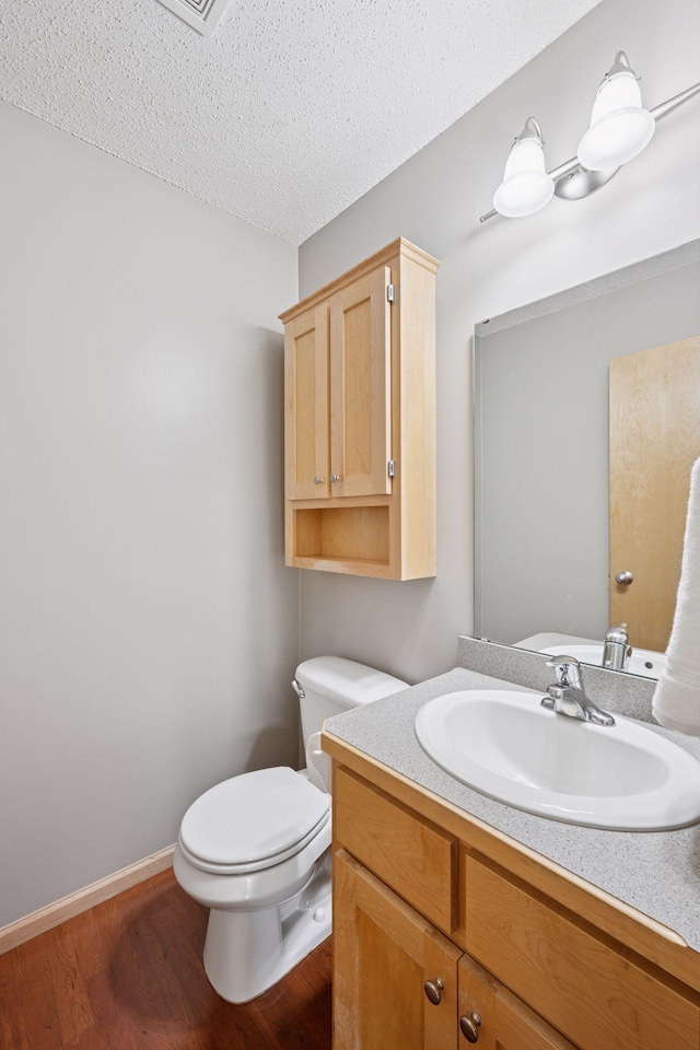 19470 Zumbro Ct NW, Elk River, MN 55330 - half bath with toilet, vanity, wood finished floors, a textured ceiling, and baseboards