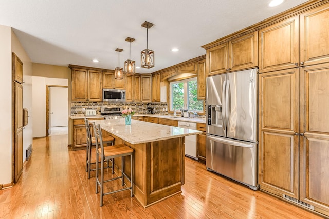 8563 72nd St S, Cottage Grove, MN 55016 - kitchen with stainless steel appliances, light wood-style floors, brown cabinets, a sink, and tasteful backsplash