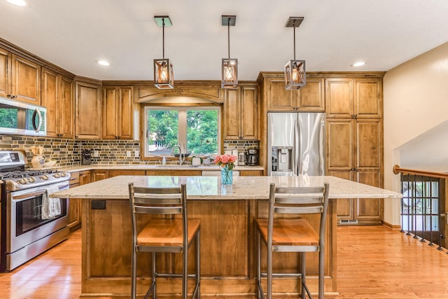 8563 72nd St S, Cottage Grove, MN 55016 - kitchen with stainless steel appliances, a sink, light stone counters, light wood-style flooring, and recessed lighting