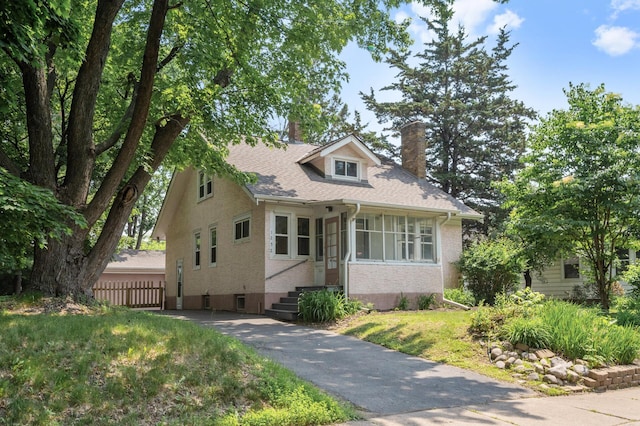 1252 Arkwright St, Saint Paul, MN 55130 - bungalow featuring a chimney, brick siding, driveway, and roof with shingles