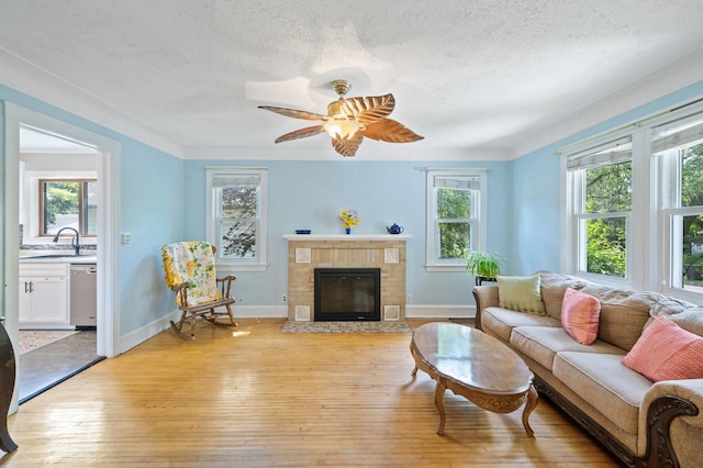 1252 Arkwright St, Saint Paul, MN 55130 - living room with a textured ceiling, light wood-style floors, a brick fireplace, and a ceiling fan
