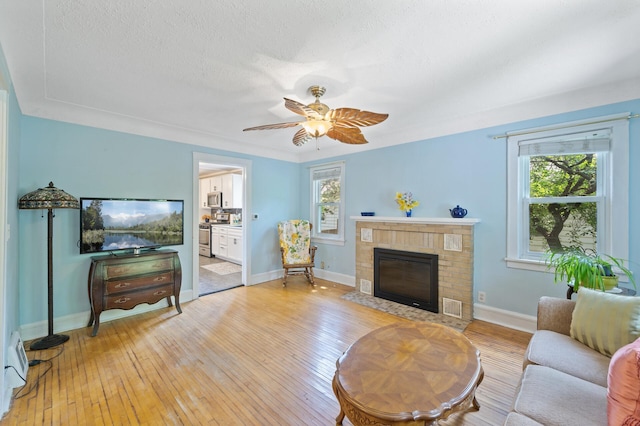 1252 Arkwright St, Saint Paul, MN 55130 - living area featuring a fireplace, light wood-style flooring, ceiling fan, and a textured ceiling