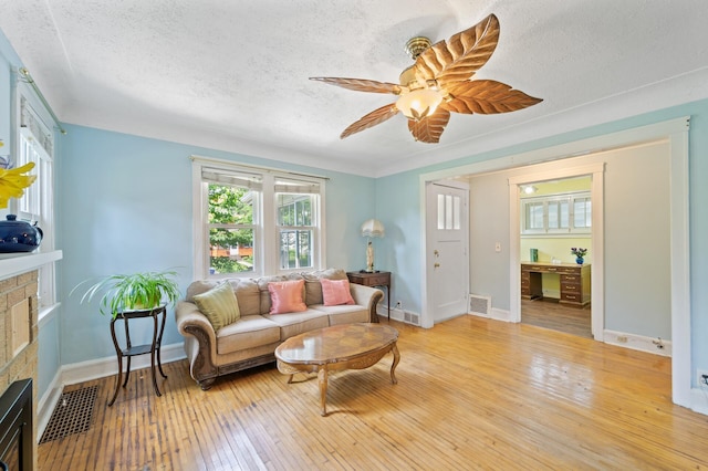 1252 Arkwright St, Saint Paul, MN 55130 - living room with a fireplace, a textured ceiling, light wood-style flooring, and a ceiling fan