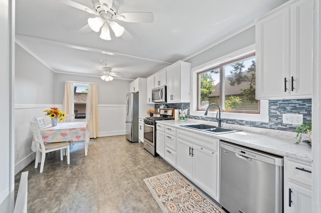 1252 Arkwright St, Saint Paul, MN 55130 - kitchen with stainless steel appliances, a wainscoted wall, a ceiling fan, white cabinetry, and tasteful backsplash