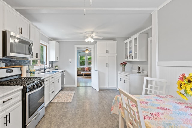 1252 Arkwright St, Saint Paul, MN 55130 - kitchen with appliances with stainless steel finishes, ceiling fan, white cabinetry, glass insert cabinets, and ornamental molding