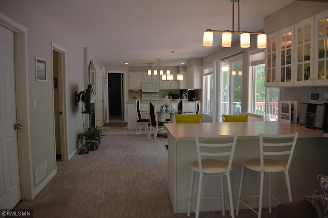 31145 409th Pl, Aitkin, MN 56431 - kitchen featuring white microwave, a peninsula, white cabinetry, glass insert cabinets, and a kitchen breakfast bar