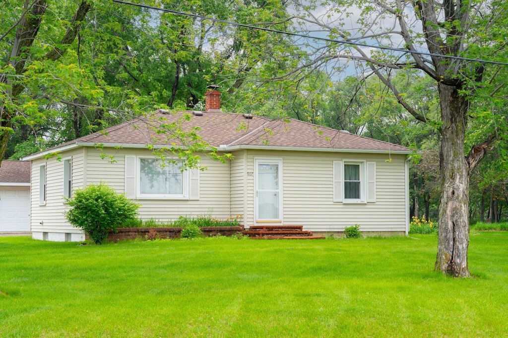 907 Elm St, Monticello, MN 55362 - view of front facade featuring a chimney, a front lawn, roof with shingles, and a garage
