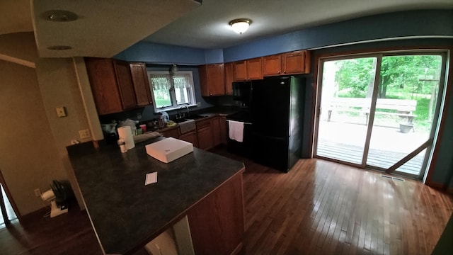 7047 Kingfisher Ln NE, Frohn Twp, MN 56601 - kitchen with freestanding refrigerator, dark countertops, dark wood-style floors, brown cabinetry, and range