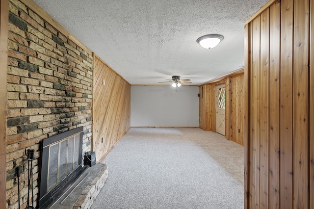 15429 Ramsey Blvd NW, Ramsey, MN 55303 - unfurnished living room featuring wood walls, a textured ceiling, carpet flooring, a brick fireplace, and ceiling fan