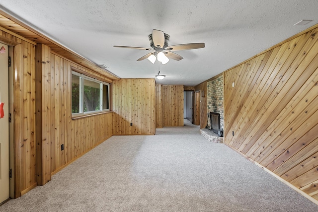 15429 Ramsey Blvd NW, Ramsey, MN 55303 - unfurnished living room with ceiling fan, carpet flooring, wood walls, a fireplace, and a textured ceiling