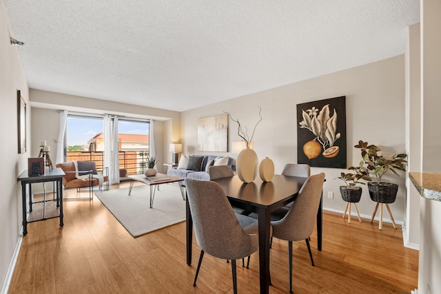 26 10th St W Unit 706, Saint Paul, MN 55102 - dining area with light wood-type flooring, a textured ceiling, and baseboards