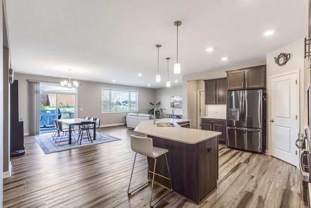 6944 Xanthus Ln N, Maple Grove, MN 55311 - kitchen with stainless steel fridge with ice dispenser, light wood-type flooring, dark brown cabinets, light countertops, and baseboards
