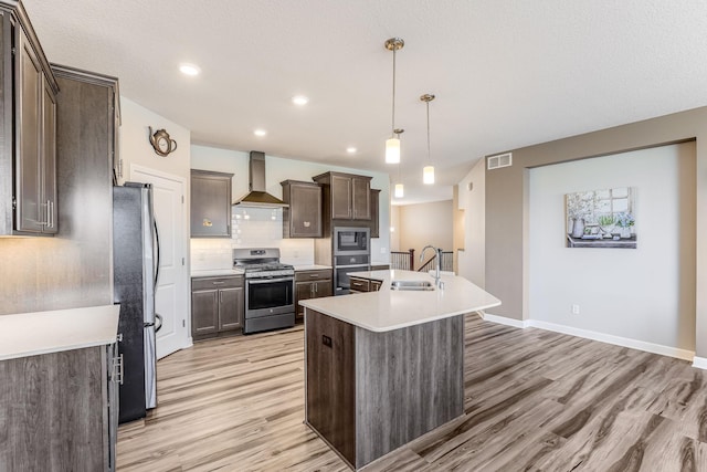 6944 Xanthus Ln N, Maple Grove, MN 55311 - kitchen featuring stainless steel appliances, wall chimney range hood, a sink, light wood finished floors, and dark brown cabinetry