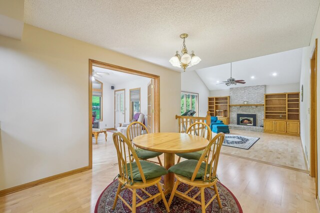 3049 12th St NW, New Brighton, MN 55112 - dining space featuring light wood finished floors, a brick fireplace, a chandelier, vaulted ceiling, and baseboards