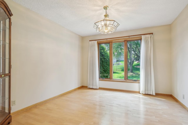 3049 12th St NW, New Brighton, MN 55112 - unfurnished room featuring light wood finished floors, a chandelier, a textured ceiling, and baseboards