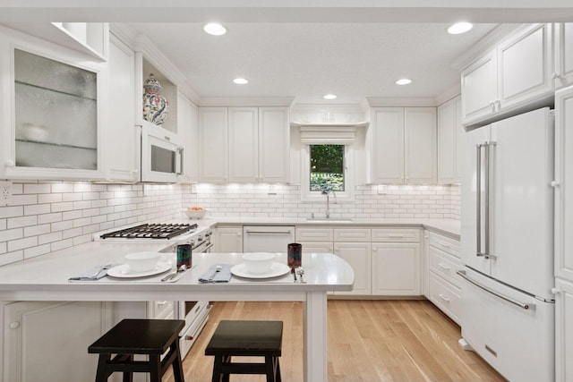 6050 Blake Ridge Rd, Edina, MN 55436 - kitchen with white appliances, light countertops, white cabinetry, a peninsula, and a breakfast bar
