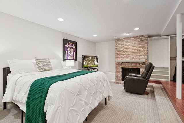 6050 Blake Ridge Rd, Edina, MN 55436 - bedroom featuring a textured ceiling, recessed lighting, wood finished floors, and a brick fireplace