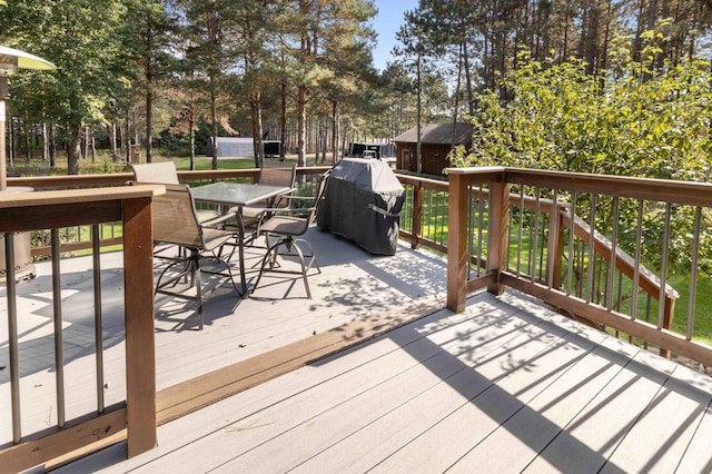 12584 County 18 SW, Brainerd, MN 56401 - wooden deck featuring outdoor dining space, view of scattered trees, grilling area, and an outdoor structure