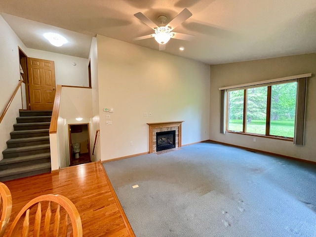 416 Rako St SW, Bemidji, MN 56601 - unfurnished living room featuring ceiling fan, a tiled fireplace, baseboards, and stairway