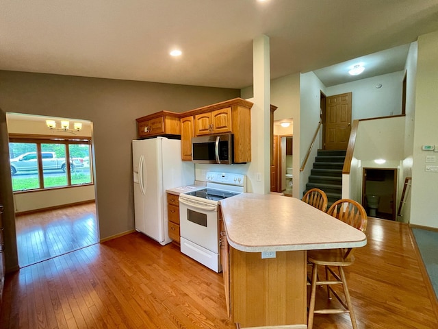 416 Rako St SW, Bemidji, MN 56601 - kitchen with white appliances, light countertops, light wood-type flooring, a kitchen bar, and baseboards