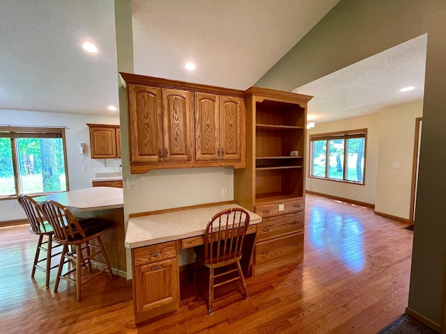 416 Rako St SW, Bemidji, MN 56601 - kitchen featuring a textured ceiling, light countertops, baseboards, light wood finished floors, and vaulted ceiling