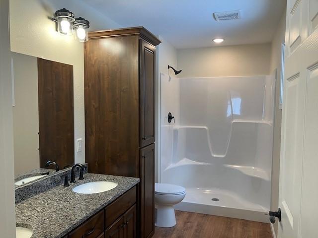7865 Ski Chalet Dr, Breezy Point, MN 56472 - bathroom featuring double vanity, wood finished floors, toilet, and a shower