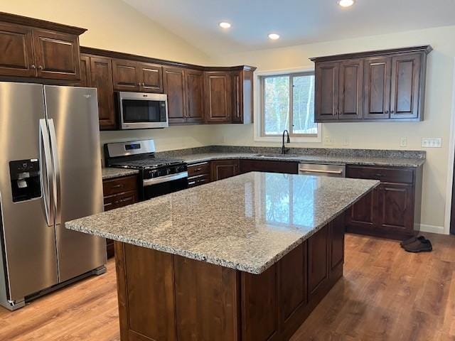 7865 Ski Chalet Dr, Breezy Point, MN 56472 - kitchen featuring appliances with stainless steel finishes, light wood-style flooring, light stone counters, dark brown cabinets, and vaulted ceiling