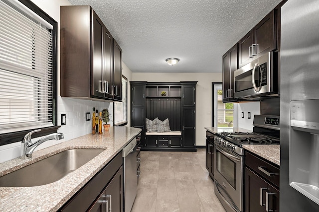 11627 Yukon St NW, Coon Rapids, MN 55433 - kitchen featuring stainless steel appliances, a sink, backsplash, light stone counters, and dark brown cabinets