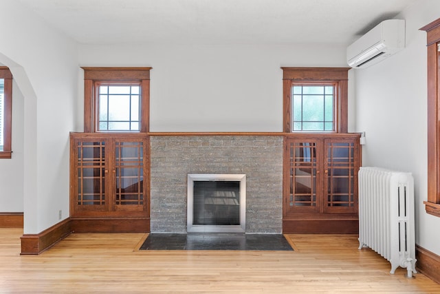 2505 Pleasant Ave, Minneapolis, MN 55404 - living room with radiator heating unit, a wall unit AC, plenty of natural light, and wood finished floors