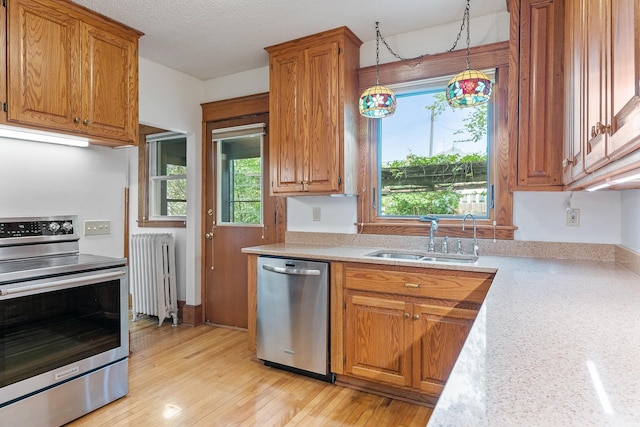 2505 Pleasant Ave, Minneapolis, MN 55404 - kitchen featuring radiator heating unit, appliances with stainless steel finishes, a sink, light countertops, and brown cabinetry