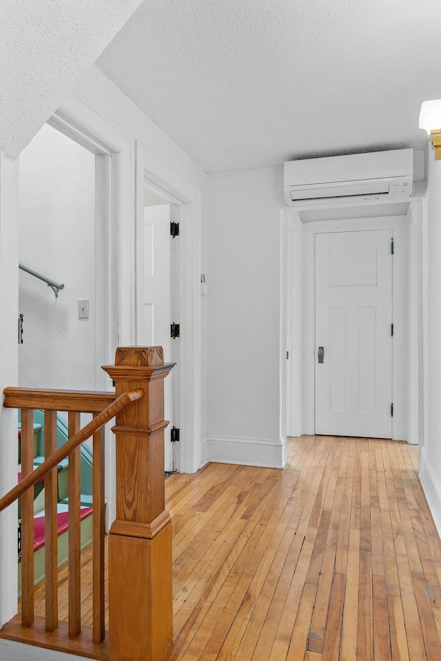 2505 Pleasant Ave, Minneapolis, MN 55404 - hallway with light wood-style floors, baseboards, a textured ceiling, and an AC wall unit