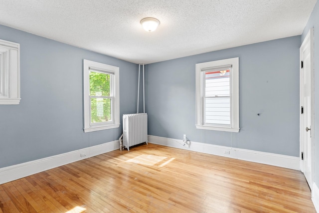 2505 Pleasant Ave, Minneapolis, MN 55404 - spare room featuring radiator, light wood-style flooring, a textured ceiling, and baseboards
