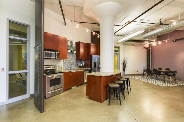 730 Stinson Blvd Unit 425, Minneapolis, MN 55413 - kitchen with appliances with stainless steel finishes, finished concrete floors, a kitchen breakfast bar, a kitchen island, and a towering ceiling