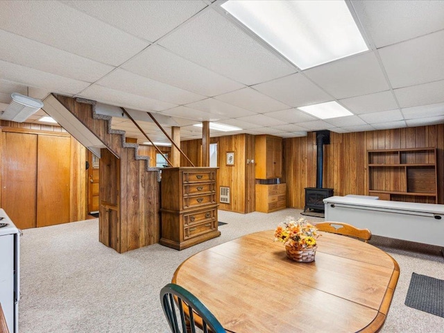 1474 Shamineau Dr, Motley, MN 56466 - dining area featuring a wood stove, carpet floors, wood walls, a drop ceiling, and stairs