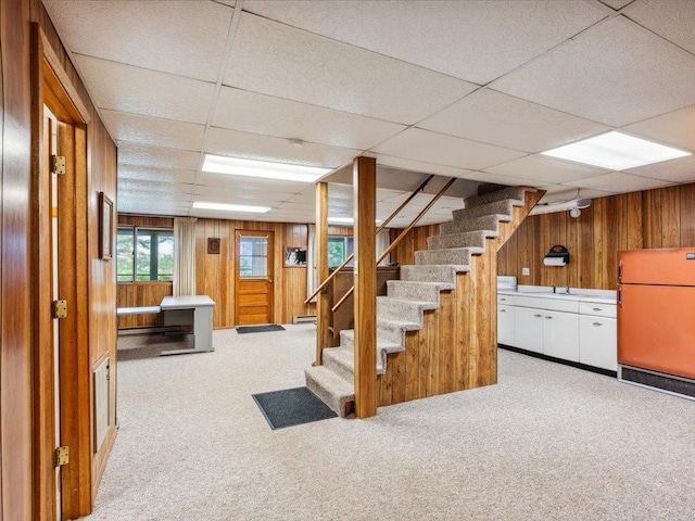 1474 Shamineau Dr, Motley, MN 56466 - basement featuring refrigerator, wooden walls, carpet flooring, a drop ceiling, and stairway