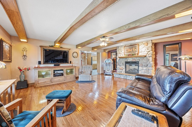 18000 10th St SW, Hawley, MN 56549 - living area featuring wood finished floors, baseboards, a stone fireplace, a ceiling fan, and beamed ceiling